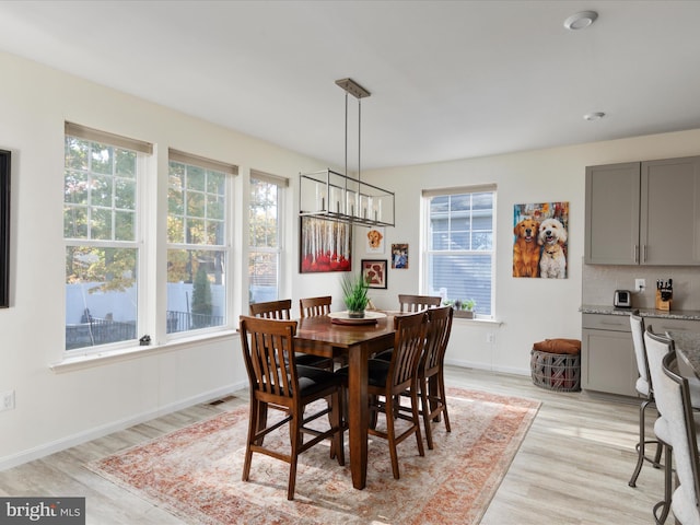 dining space with a notable chandelier, light hardwood / wood-style floors, and plenty of natural light