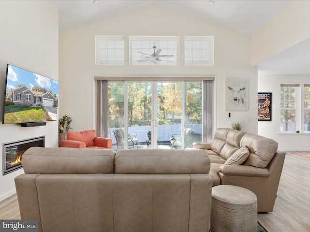 living room with light hardwood / wood-style flooring, a healthy amount of sunlight, high vaulted ceiling, and ceiling fan