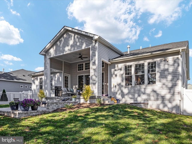 rear view of property with a patio, ceiling fan, and a yard