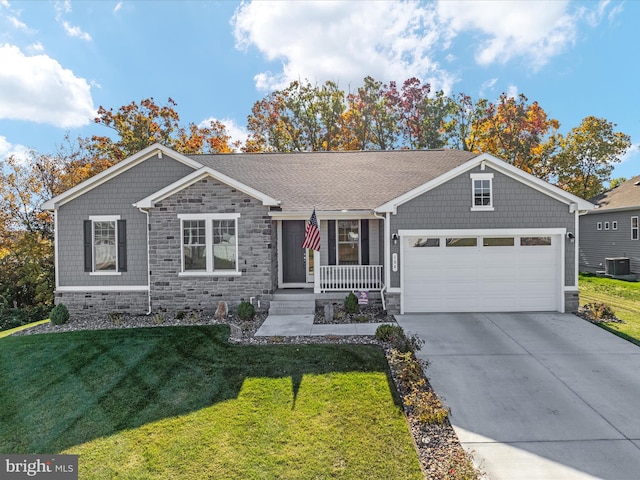 view of front facade with a front yard, cooling unit, a porch, and a garage