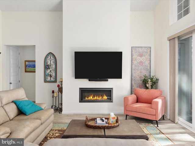 living room with light hardwood / wood-style floors and a towering ceiling