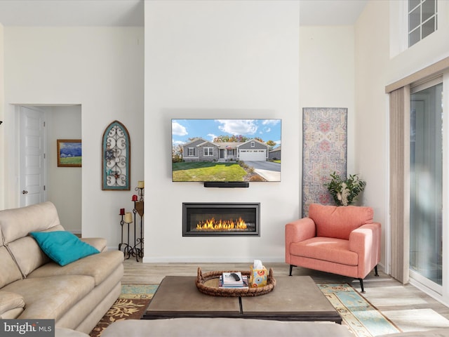 living room with a towering ceiling and light wood-type flooring