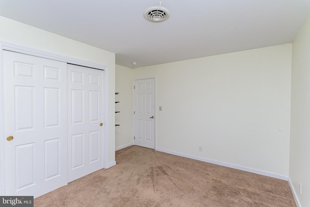 unfurnished bedroom featuring light carpet and a closet