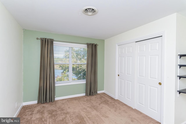 unfurnished bedroom with light carpet and a closet