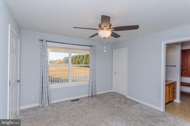 unfurnished bedroom with connected bathroom, light carpet, and ceiling fan