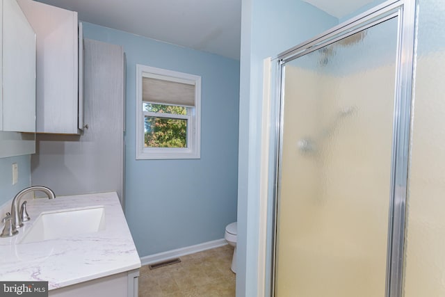 bathroom featuring a shower with door, vanity, and toilet