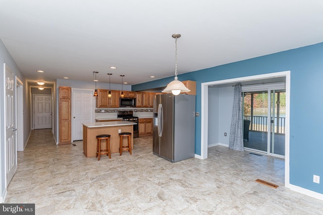 kitchen with hanging light fixtures, a breakfast bar area, black appliances, and a center island