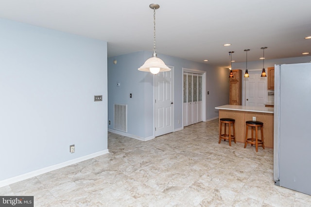 kitchen with a breakfast bar, decorative light fixtures, and white fridge