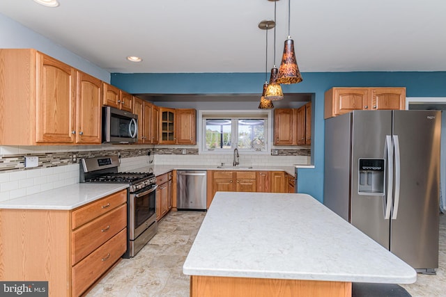 kitchen featuring stainless steel appliances, backsplash, hanging light fixtures, sink, and a center island