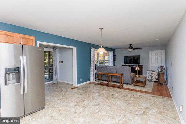 kitchen featuring stainless steel refrigerator with ice dispenser, ceiling fan, light brown cabinetry, decorative light fixtures, and light wood-type flooring