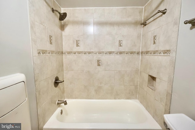 bathroom featuring washer / clothes dryer, toilet, and tiled shower / bath