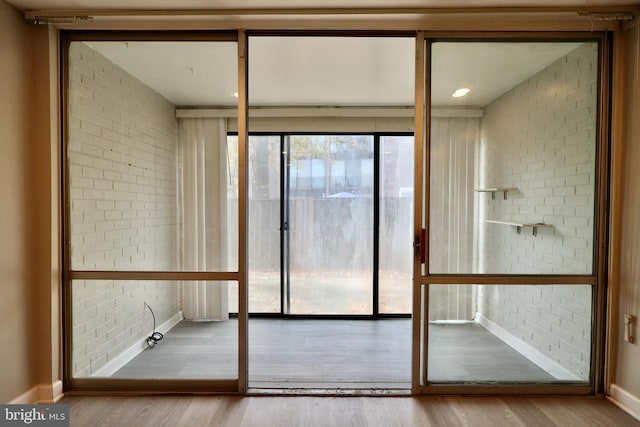 bathroom with hardwood / wood-style floors and brick wall