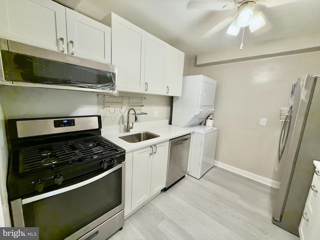 kitchen with sink, stainless steel appliances, stacked washer / dryer, light hardwood / wood-style floors, and white cabinets