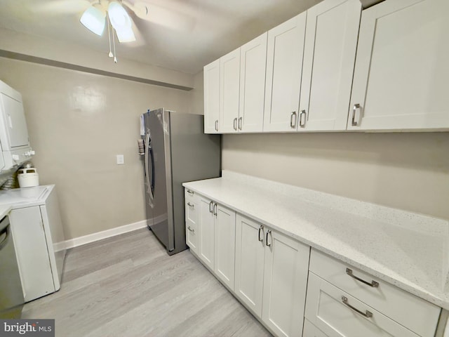 kitchen featuring white cabinets, stainless steel fridge, light wood-type flooring, and stacked washer and clothes dryer