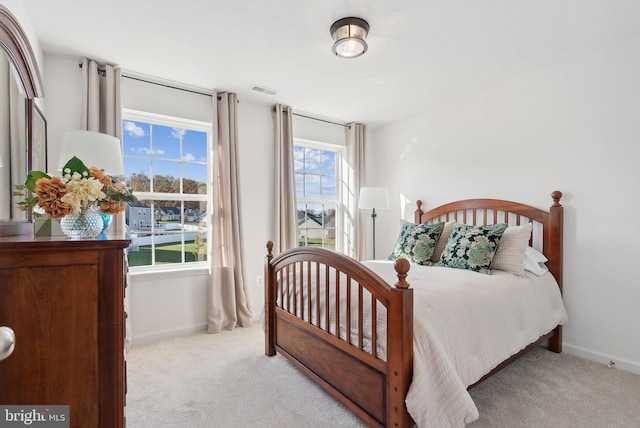 bedroom featuring light carpet and multiple windows