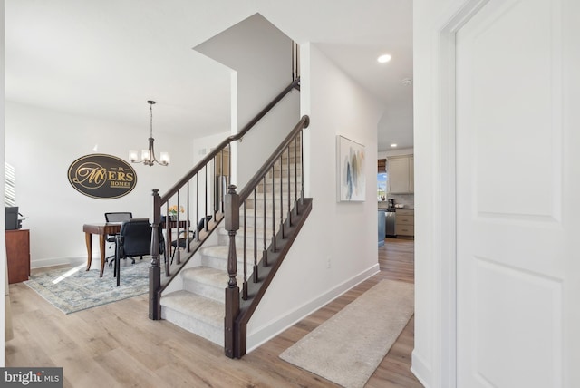 stairway featuring hardwood / wood-style floors and an inviting chandelier