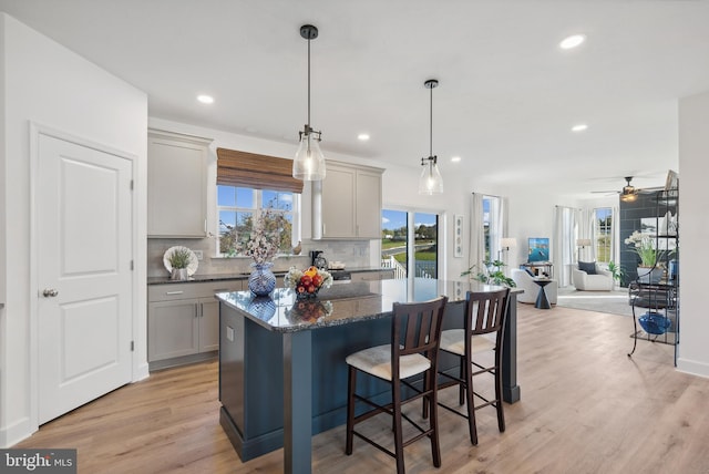 kitchen with a healthy amount of sunlight, a center island, pendant lighting, and gray cabinetry