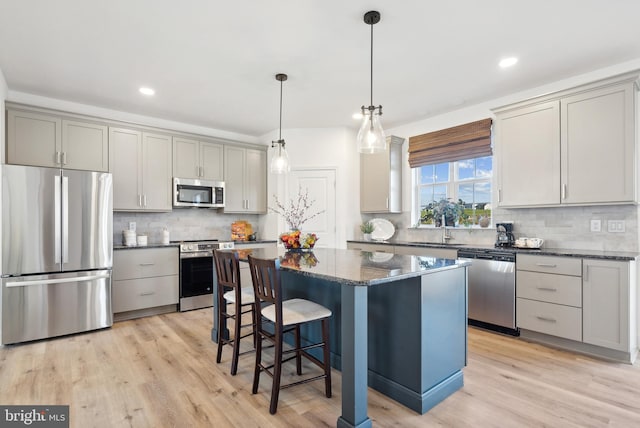 kitchen with gray cabinets, a center island, appliances with stainless steel finishes, and light wood-type flooring