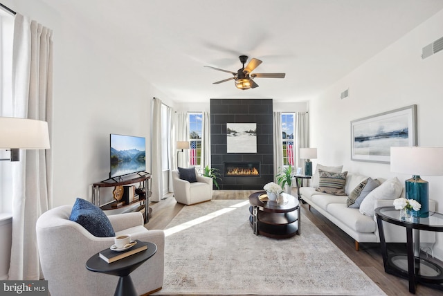 living room with hardwood / wood-style flooring, a tile fireplace, and ceiling fan