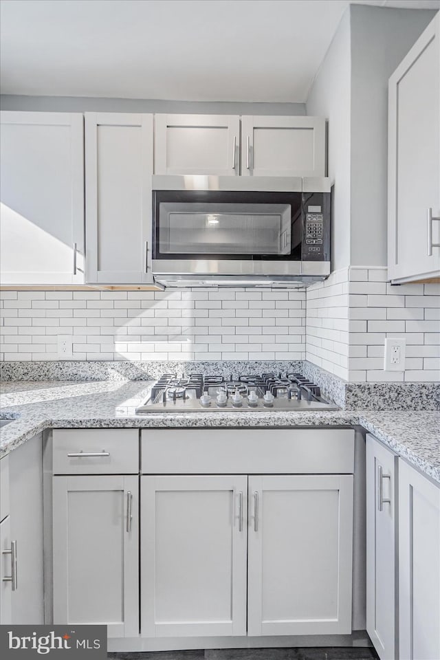 kitchen featuring white cabinets, tasteful backsplash, gas stovetop, and light stone countertops