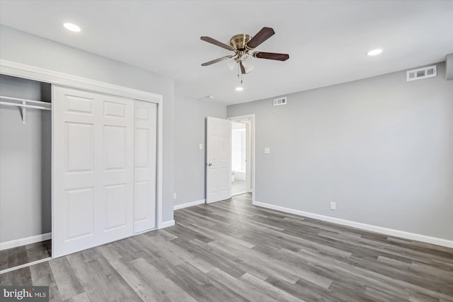 unfurnished bedroom with wood-type flooring, a closet, and ceiling fan