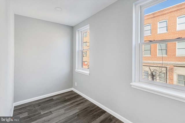 spare room featuring dark wood-type flooring and plenty of natural light