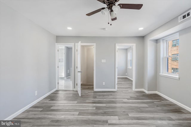 unfurnished bedroom featuring ensuite bath, ceiling fan, and light hardwood / wood-style floors