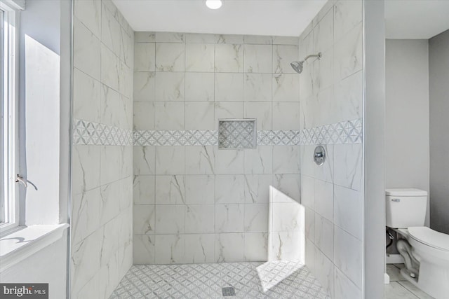 bathroom featuring toilet and a tile shower