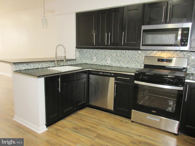 kitchen featuring sink, light hardwood / wood-style flooring, stainless steel appliances, and kitchen peninsula