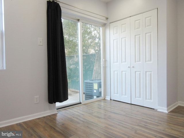 unfurnished bedroom featuring wood-type flooring, a closet, and access to outside