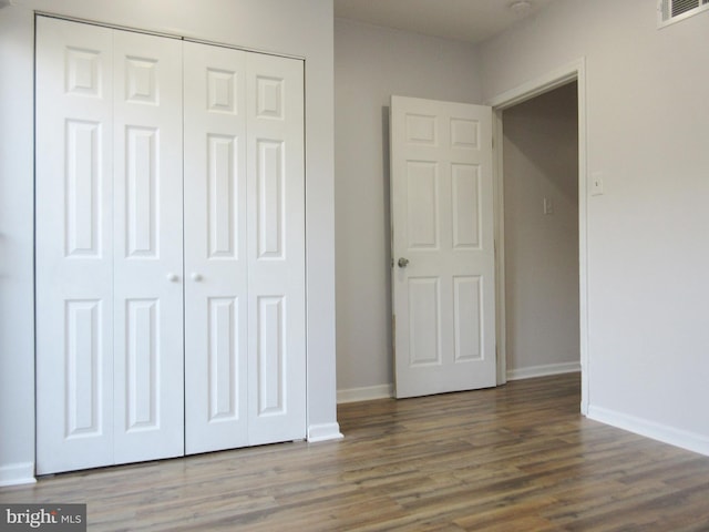 unfurnished bedroom featuring dark hardwood / wood-style floors and a closet