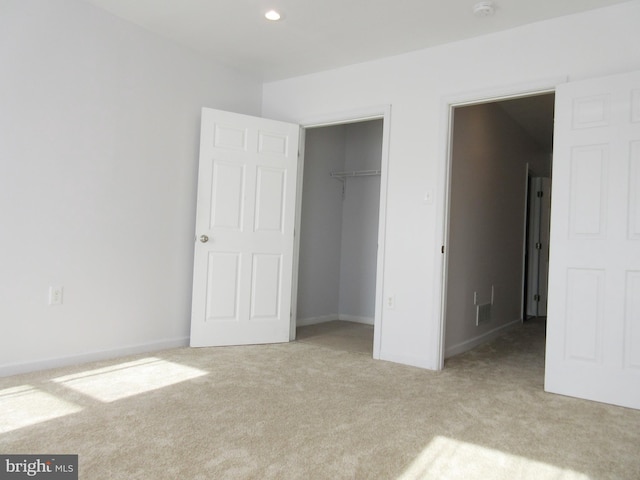 unfurnished bedroom with light colored carpet and a closet