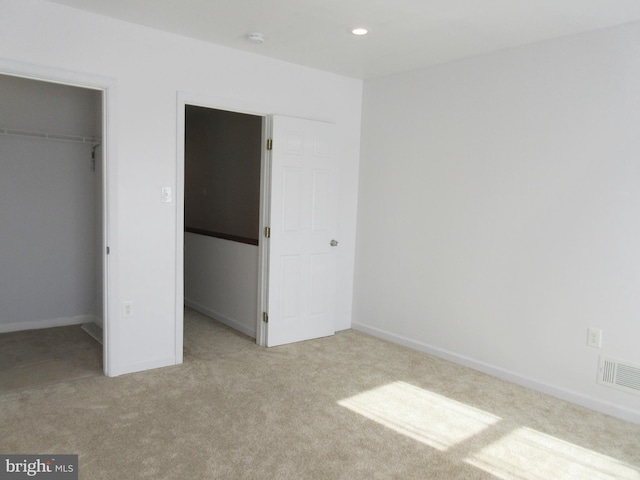 unfurnished bedroom featuring a spacious closet, light colored carpet, and a closet