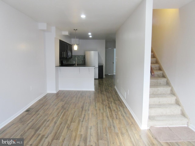 kitchen with hardwood / wood-style flooring, hanging light fixtures, backsplash, and kitchen peninsula