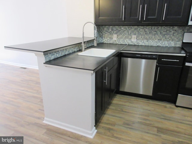 kitchen featuring appliances with stainless steel finishes, tasteful backsplash, sink, light hardwood / wood-style floors, and kitchen peninsula