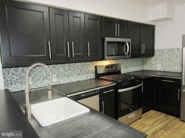 kitchen featuring stainless steel appliances, sink, backsplash, and light hardwood / wood-style flooring