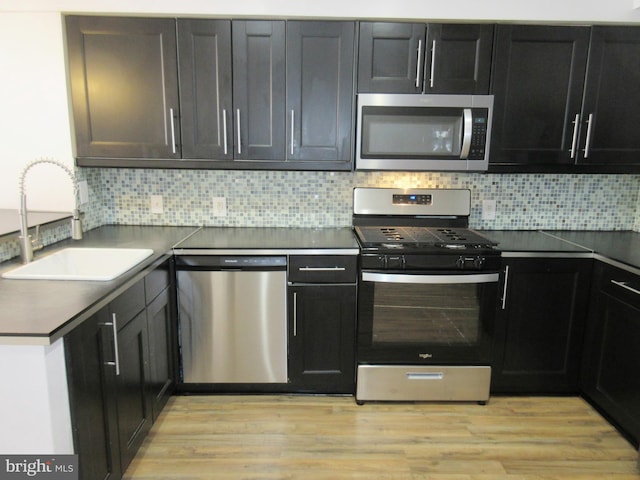 kitchen with appliances with stainless steel finishes, sink, backsplash, and light wood-type flooring