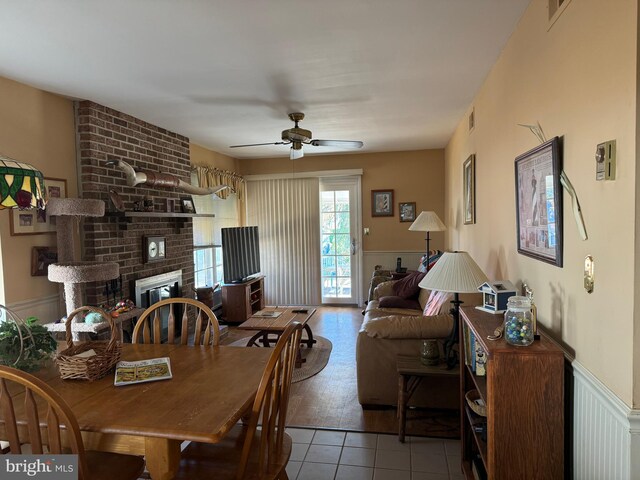 dining space featuring ceiling fan, light tile patterned floors, and a fireplace