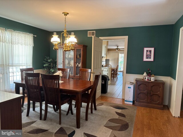 dining space with light hardwood / wood-style floors and ceiling fan with notable chandelier