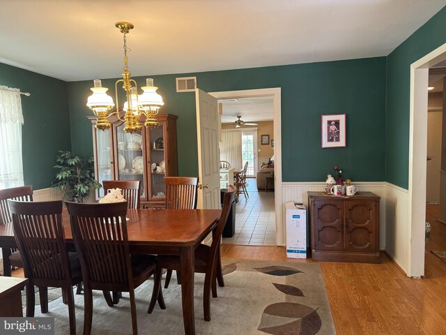 dining space with light hardwood / wood-style floors and ceiling fan with notable chandelier