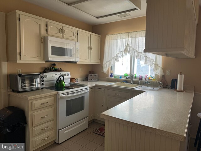 kitchen featuring kitchen peninsula, sink, light tile patterned floors, and white appliances