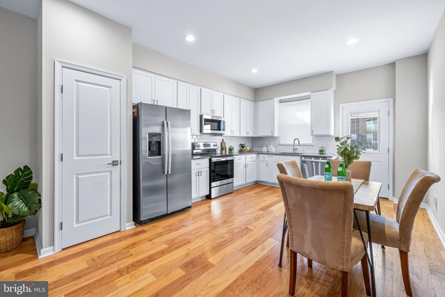 1020 N Eden St, Baltimore, MD 21205 - kitchen featuring appliances with stainless steel finishes, light wood finished floors, white cabinetry, decorative backsplash, and recessed lighting