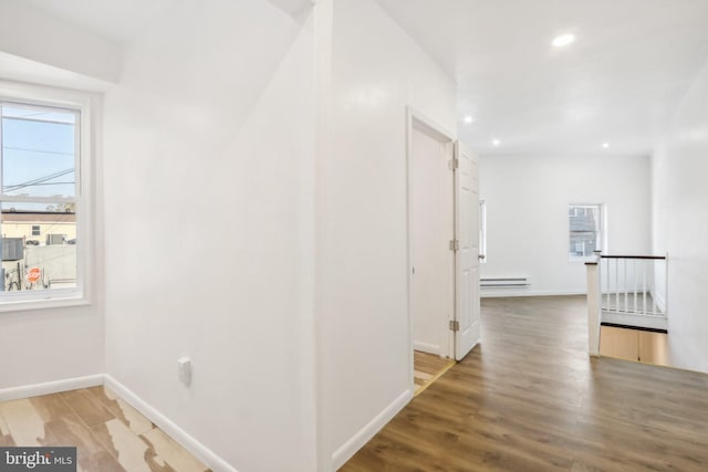 corridor with a baseboard heating unit and wood-type flooring