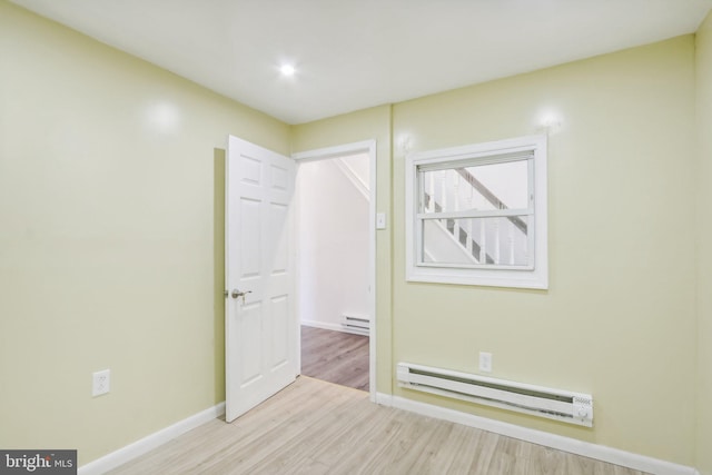 empty room featuring a baseboard heating unit and light wood-type flooring