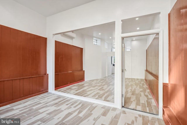 spare room with a wall unit AC and wood walls