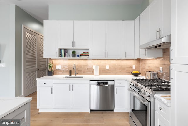 kitchen with appliances with stainless steel finishes, sink, light wood-type flooring, and white cabinets