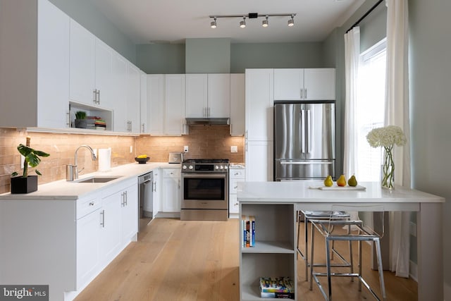 kitchen with light hardwood / wood-style floors, white cabinetry, stainless steel appliances, and sink