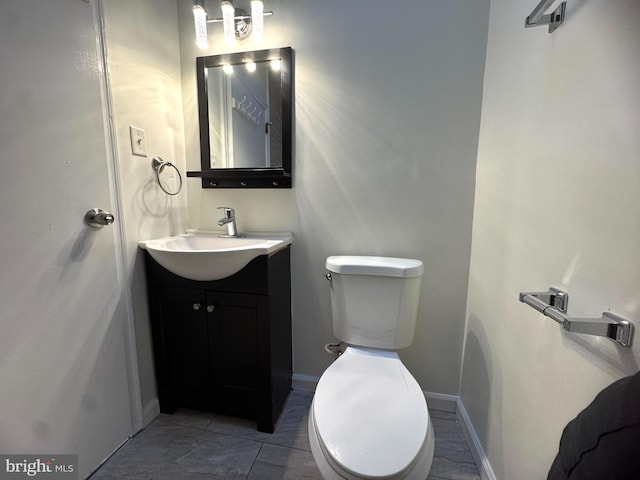 half bath featuring vanity, toilet, and baseboards