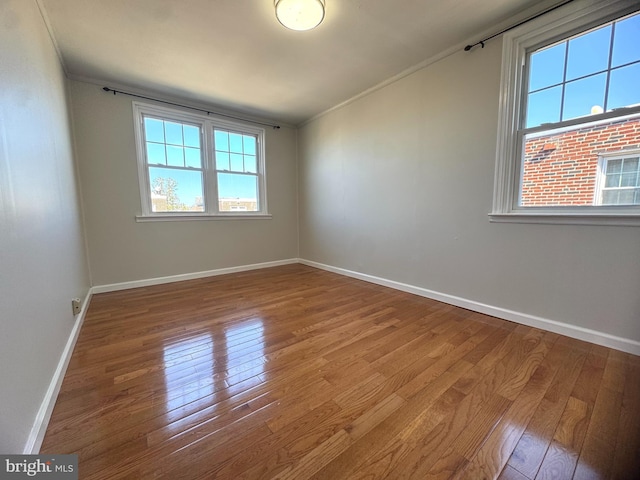 unfurnished room featuring baseboards, wood finished floors, and ornamental molding