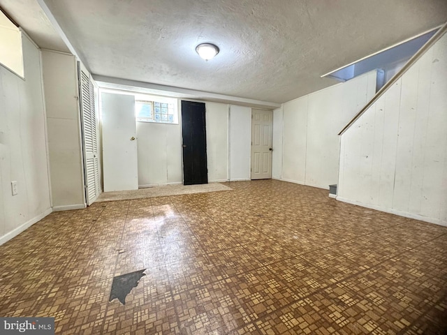 basement with wooden walls and a textured ceiling
